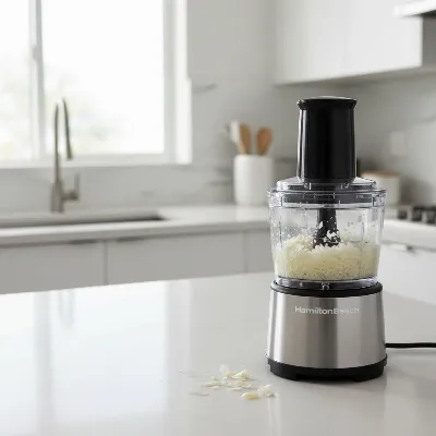 A Hamilton Beach mini food chopper on a clean kitchen counter, actively chopping ingredients for a meal prep task.