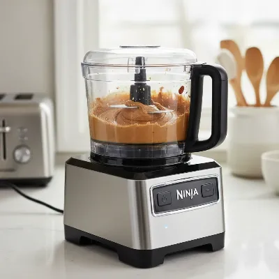 A sleek Ninja Professional Plus Food Processor making creamy peanut butter with its unique stacked blades visible in action.